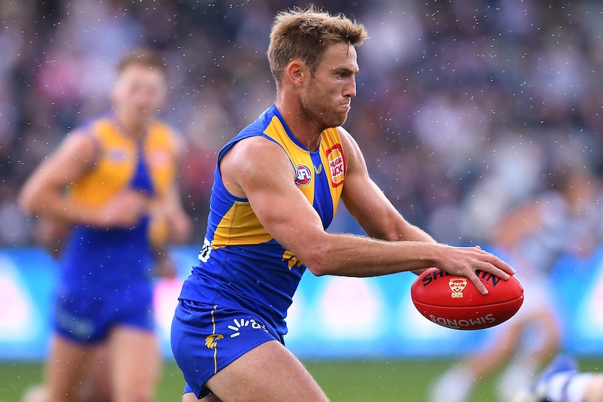 Brad Sheppard is about to drop the ball onto his boot as rain falls around him