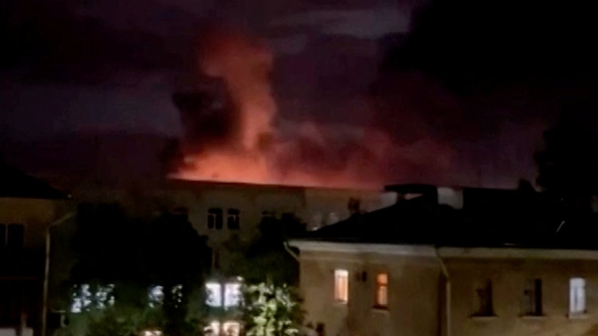 A plume of smoke is illuminated by a flash of light amid a drone attack in Russia.