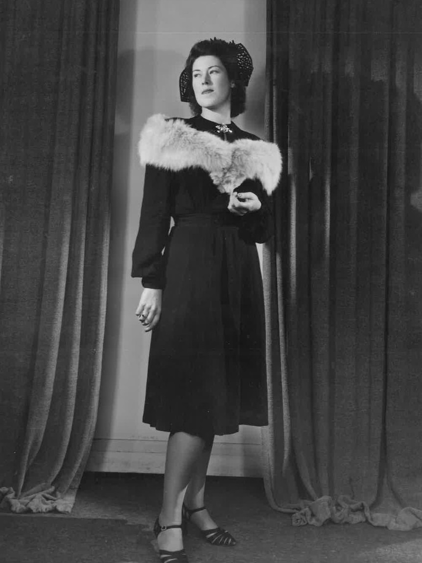 An old black and white photo of an elegant lady in a  black dress and fox fur