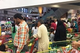 Crowds of people line up at supermarket checkouts
