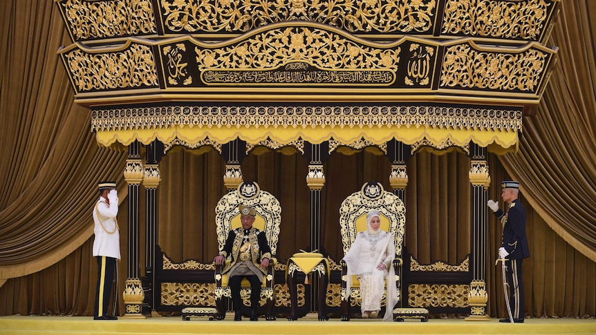 The new Malaysian king and queen sit on lavish thrones and sit under an elaborate canopy of estate