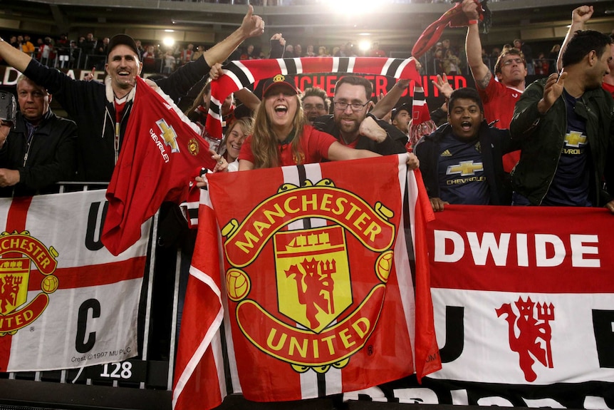 Cheering fans waving Manchester United flags.