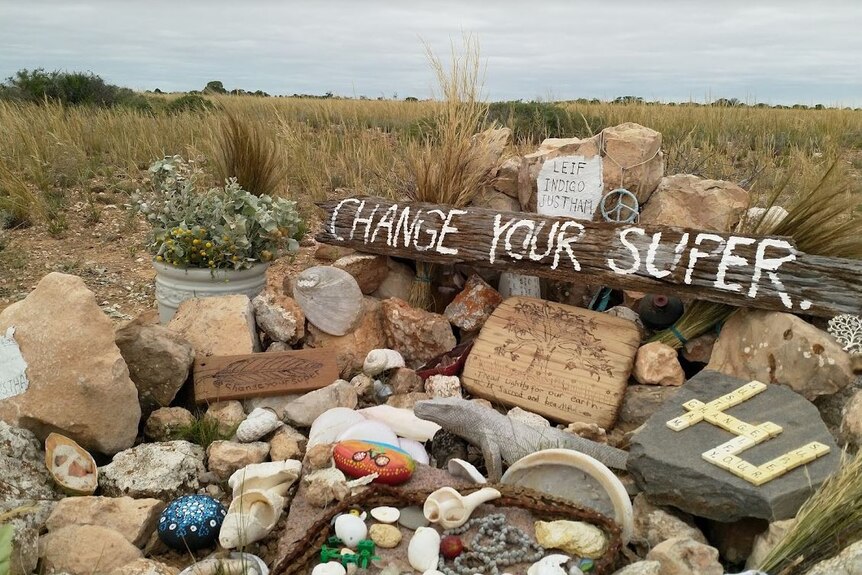 A memorial on the side of the road with a sign stating "change your super"