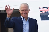 Malcolm Turnbull waves as he boards a plane