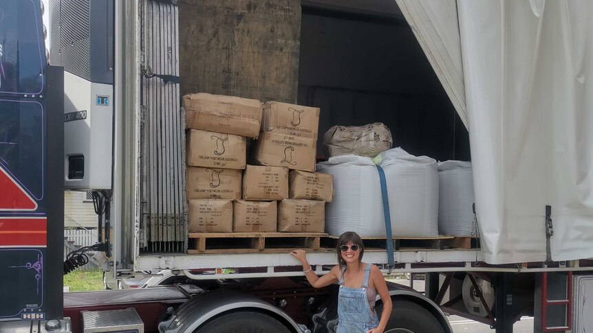 A woman stands beside a truck with two pallets of thongs