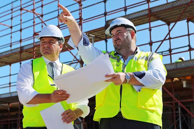 two men stand at a building site 