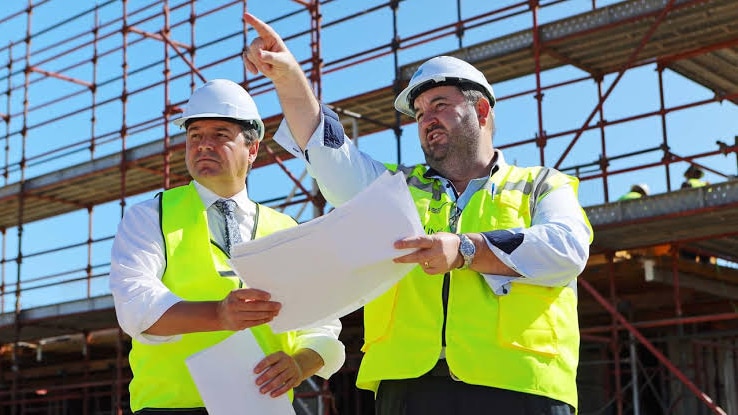 two men stand at a building site 