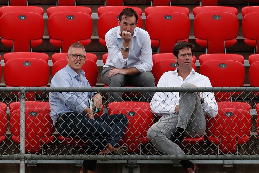 Steven Hocking and Gillon McLachlan sit in front of Andrew Dillon at an AFL ground.