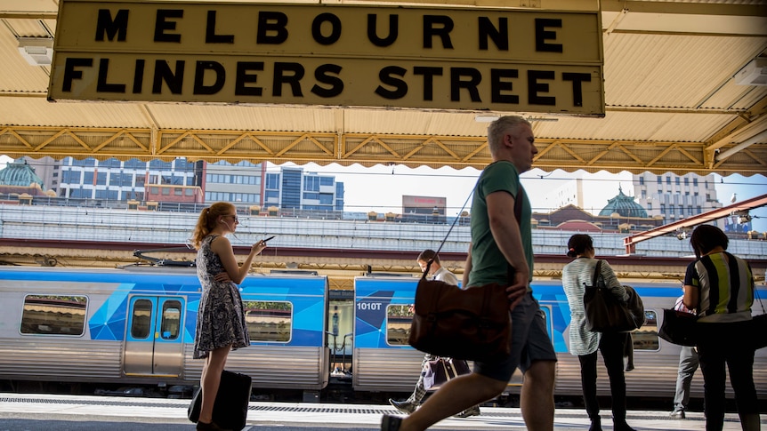 A train platform at Flinders Street station showing patrons and a sign on March 14, 2017.
