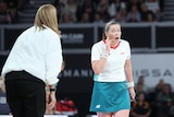 Nicole Richardson shouts at an umpire who holds her ear and shouts back