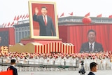 Performers travel past Tiananmen Square with a float showing a large portrait of Chinese President Xi Jinping