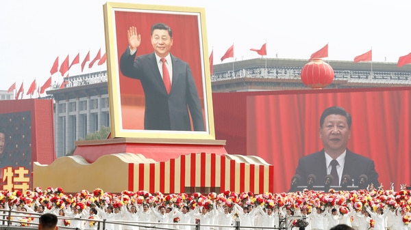 Performers travel past Tiananmen Square with a float showing a large portrait of Chinese President Xi Jinping