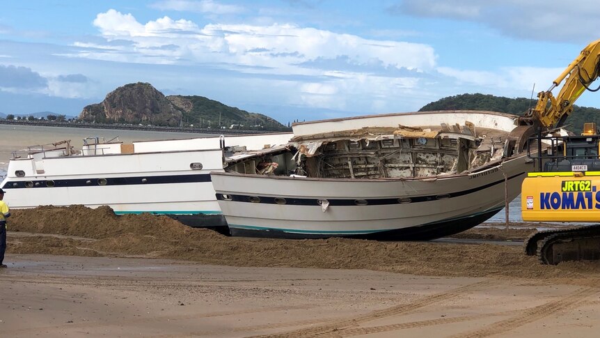 Boat wreckage next to machinery on a beach