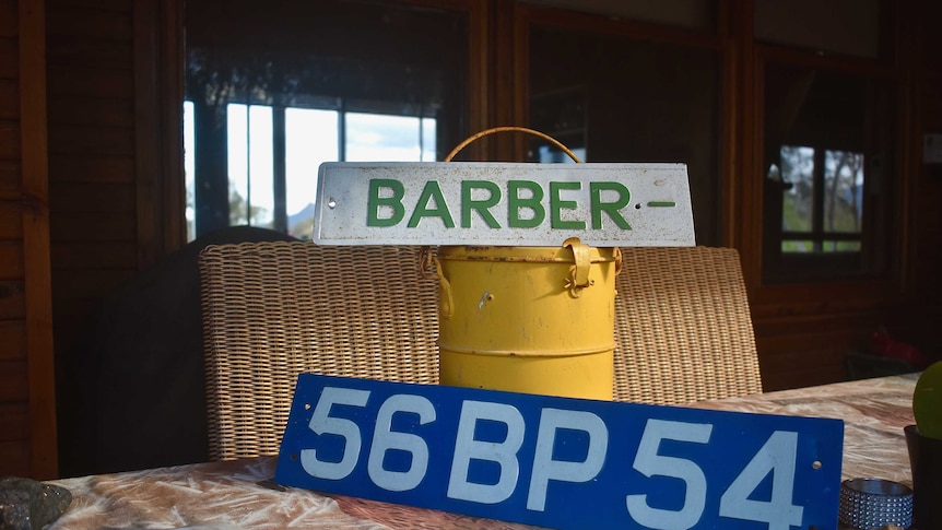 Two old number plates rest on a yellow bucket-like object