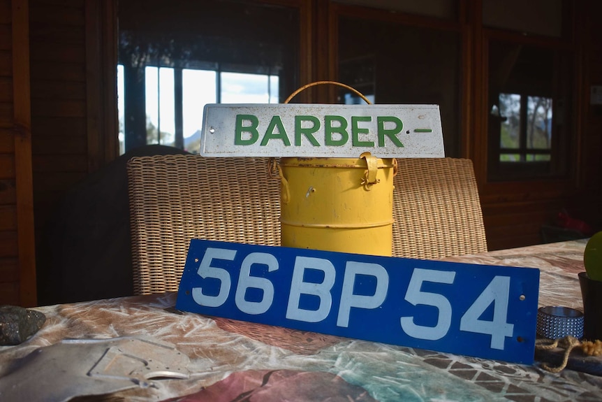 Two old number plates rest on a yellow bucket-like object