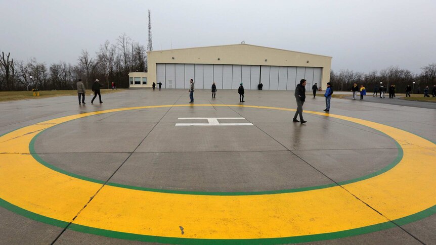 Anti-government protesters and journalists walk on a helipad at Viktor Yanukovych's residence.