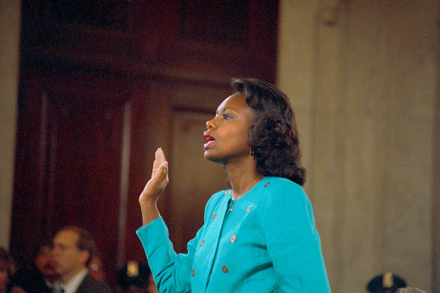 Anita Hill with one hand in the air