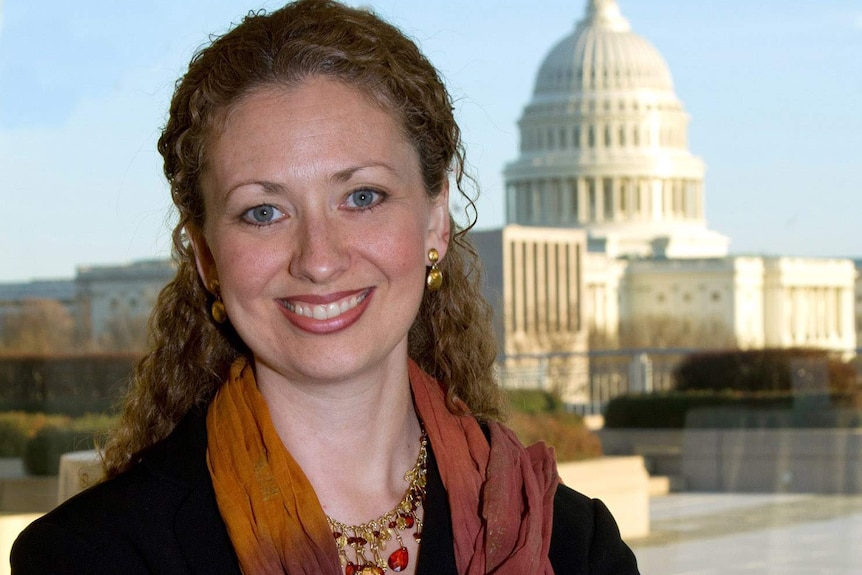 A woman in a suit and shawl smiles at the camera.