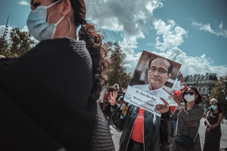 A protester holding a sign bearing the face of Zaw Wai Soe