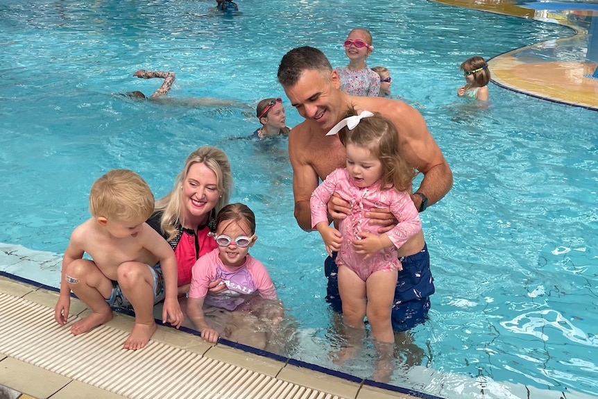 A man and a woman with three children in a pool