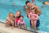 A man and a woman with three children in a pool