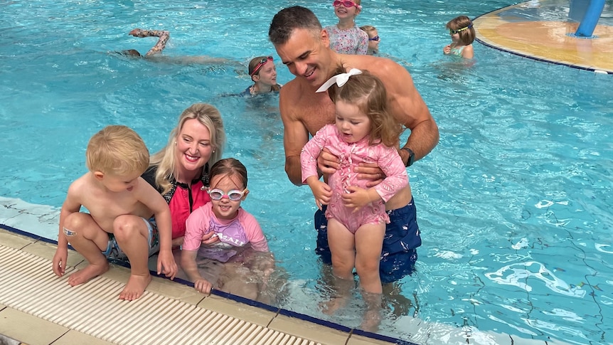 A man and a woman with three children in a pool