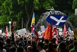 A large crowd waves flags at an anti-COVID protest rally