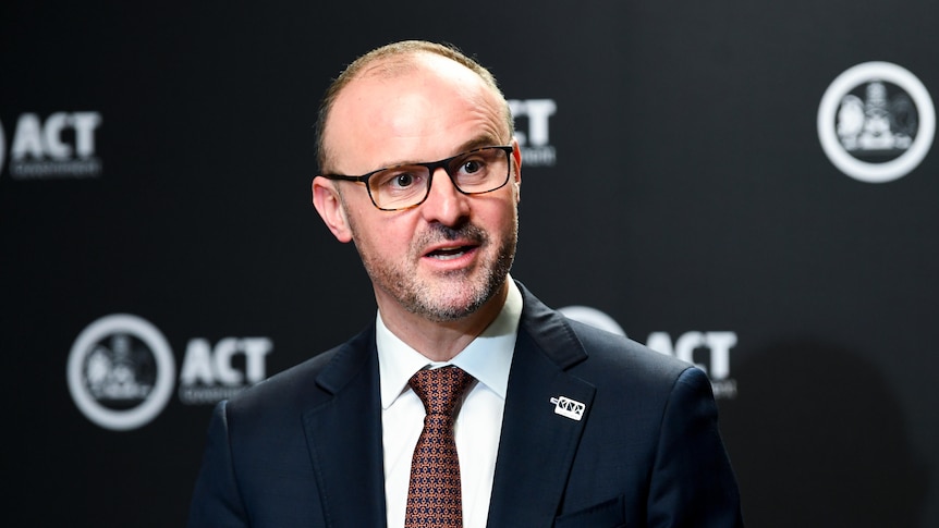 Andrew Barr in front of a background with the ACT government logo on it.