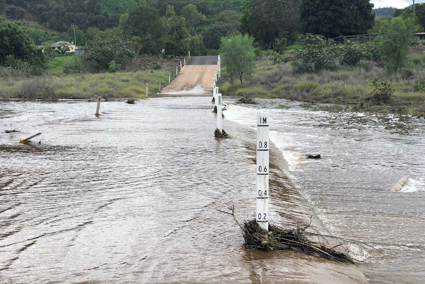A road crossing over a river is flooded over with water.