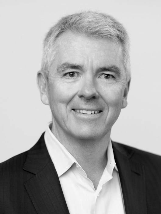 Steve Bellotti in a black and white photo, he is wearing a suit with grey hair.