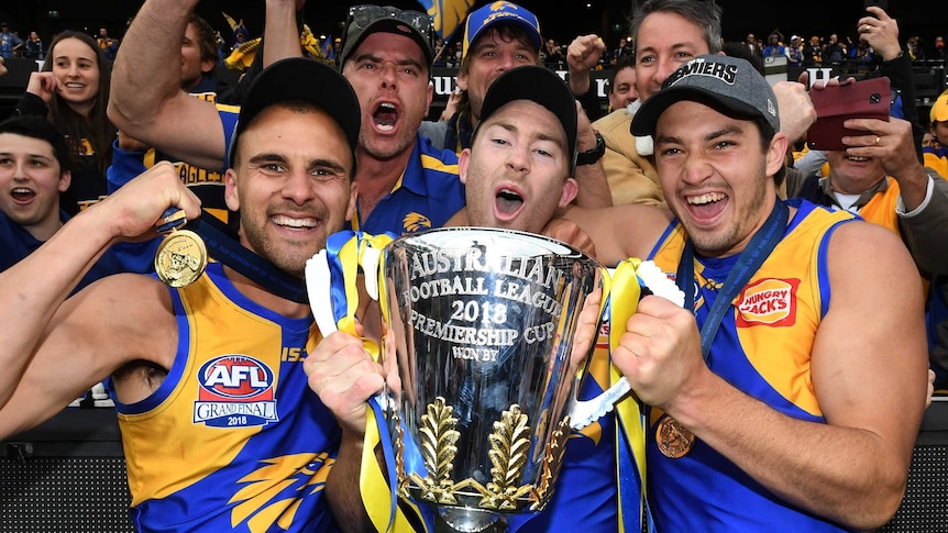 Dom Sheed, Jeremy McGovern and Liam Duggan hold the AFL premiership trophy at the MCG after beating Collingwood.