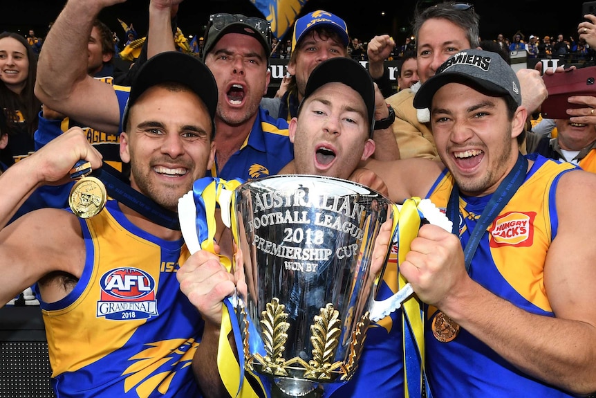 Dom Sheed, Jeremy McGovern and Tom Barrass hold the AFL premiership trophy in front of Eagles fans