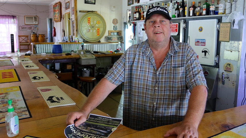Man wearing cap stands behind bar in pub 