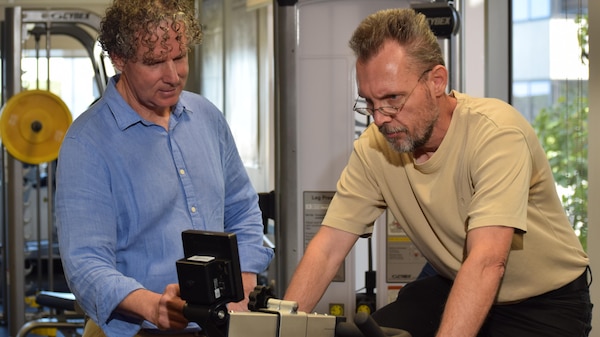 Curtin School of Allied Health Professor Peter O'Sullivan looks on as trial participant Volker Rehbocks rides an exercise bike.