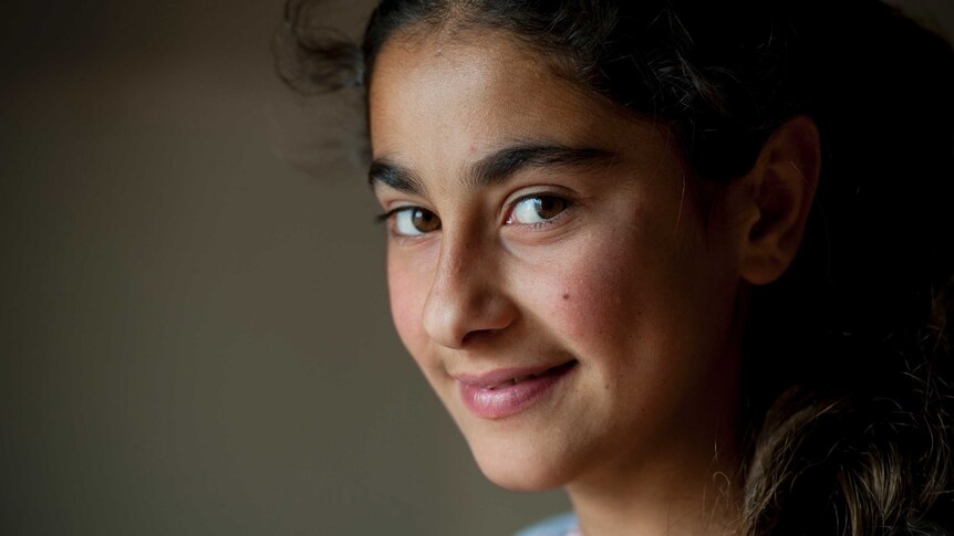 A teenage Syrian girl smiles in an Iraqi refugee camp