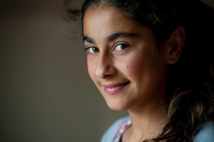 A teenage Syrian girl smiles in an Iraqi refugee camp