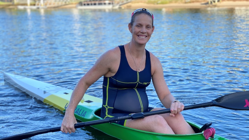 Pregnant woman sitting in kayak and smiling.