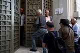 A National Bank official opens the door of a bank branch while people wait to enter in Athens, Greece July 20, 2015.