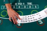 A blurred image of cards being spread on a green black jack table.