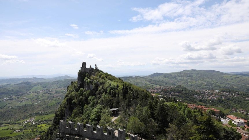 scenic green landscape, seen from high view.  In centre, a jagged bluff with buildings along its ridge