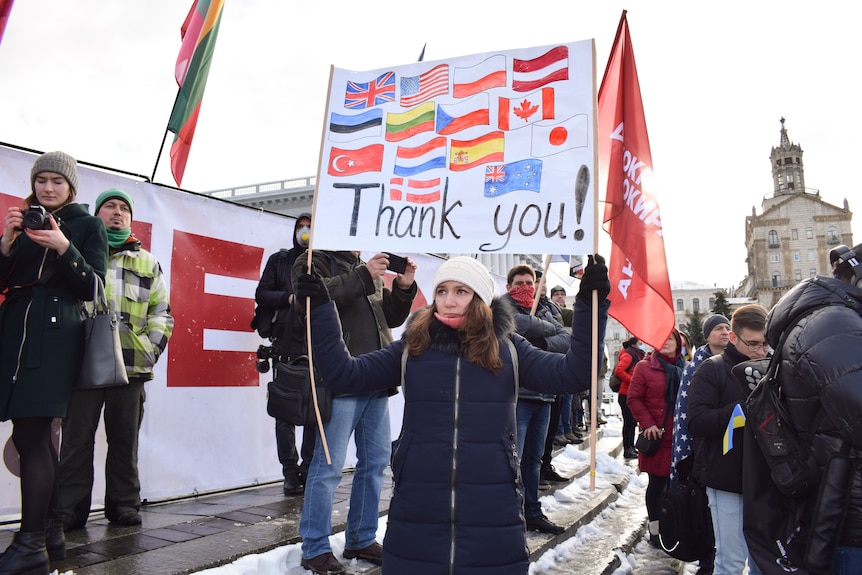 Un groupe de personnes portant des drapeaux se tient debout sur une place.