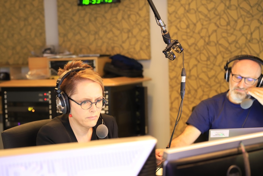 A woman and a man in a radio studio with headphones on.