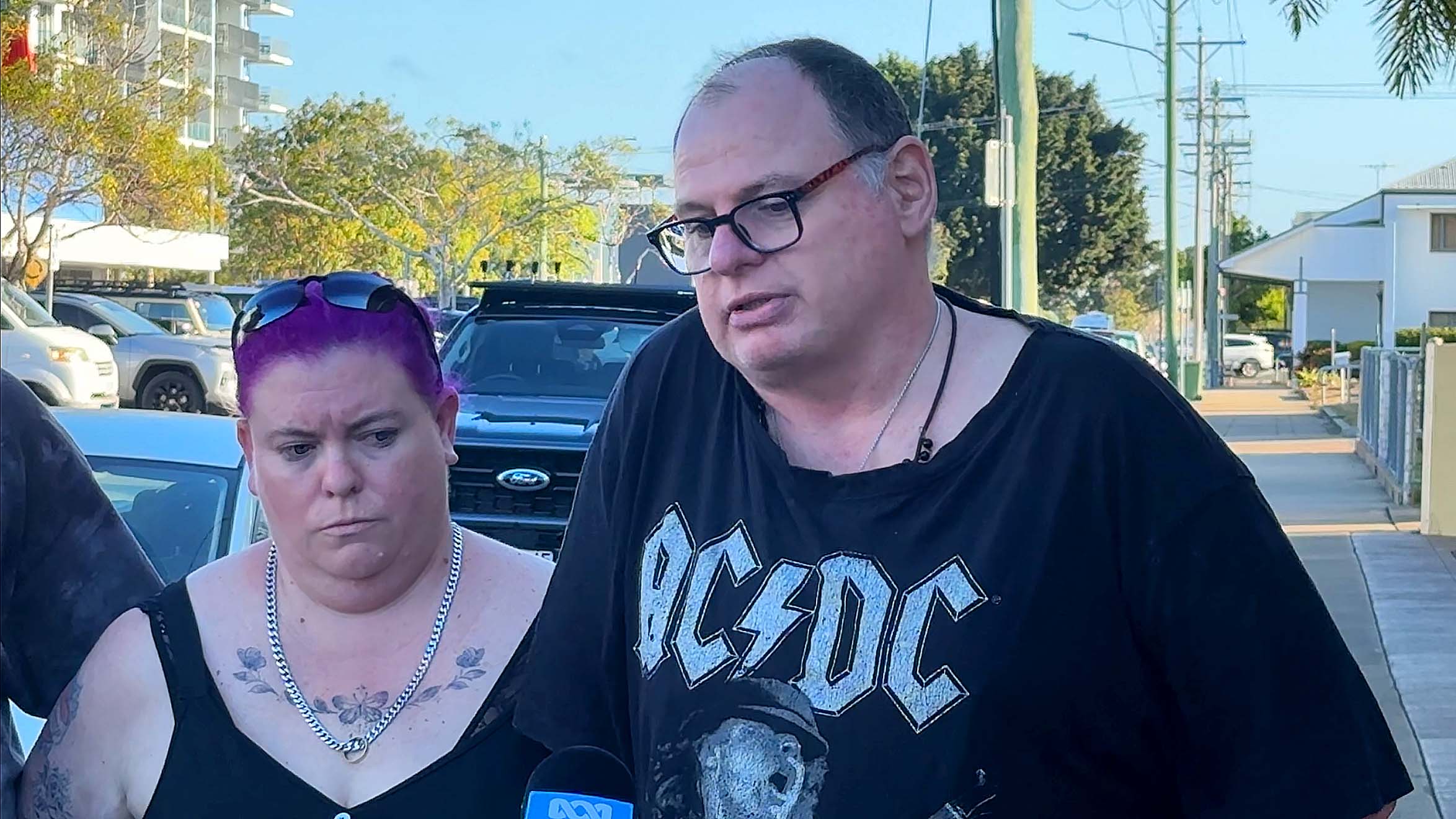 A man and a woman look down sadly outside the court house.