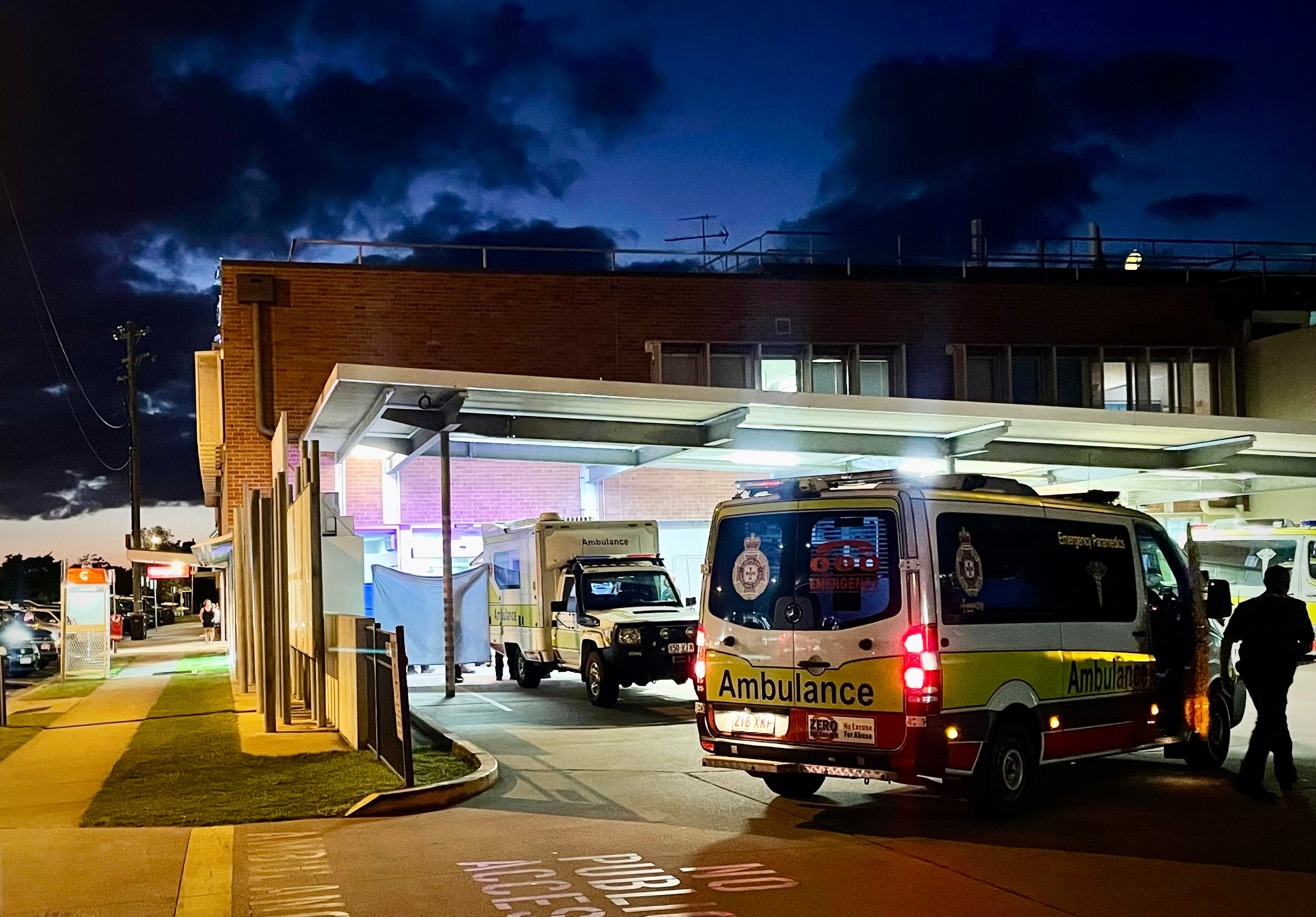ambulances arrive at bundaberg hospital, a paramdic holds up tarpauline to block view