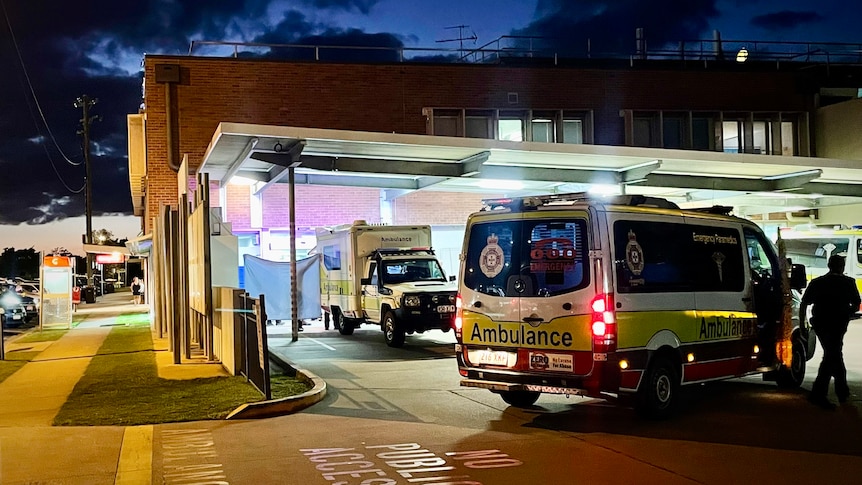 ambulances arrive at bundaberg hospital, a paramdic holds up tarpauline to block view