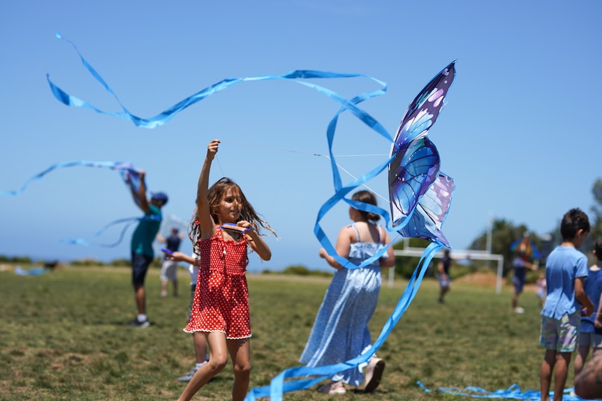 Children hold kites at a park