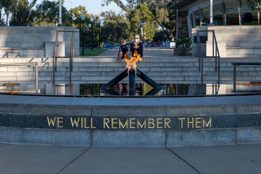 A woman and a child sit alone at the Pool of Remembrance in Kings Park.