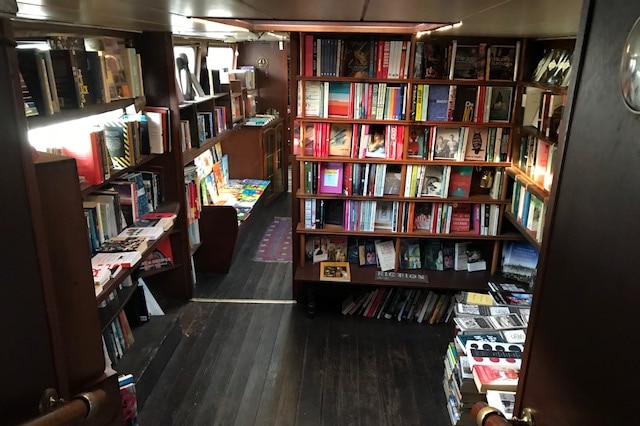 A number of books sit on shelves in London's canal boat bookshop.