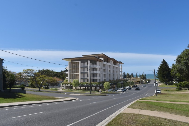 Artist's impression of a unit complex on a corner, road in the foreground, blue sky and ocean in the background.