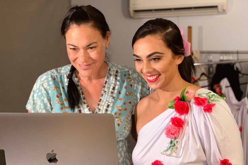 Two women stand looking at a computer